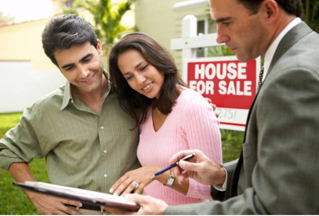 Couple reviewing home loan paperwork with an agent in front of a house for sale in Florida.