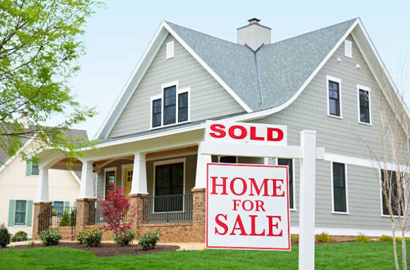 Front exterior of a sold home with a for sale sign, showing curb appeal and a successful home sale.