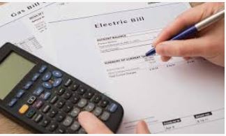 Person reviewing an electric bill with a calculator, showing typical monthly utility costs for homeowners in Citrus County and Marion County.