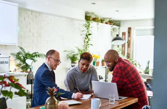 Couple reviewing homeowners insurance options with an agent at a kitchen table in a Florida home.