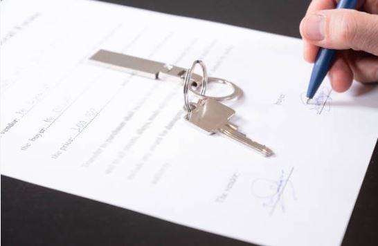 Homebuyer signing paperwork with house keys on top of the title documents in Citrus County